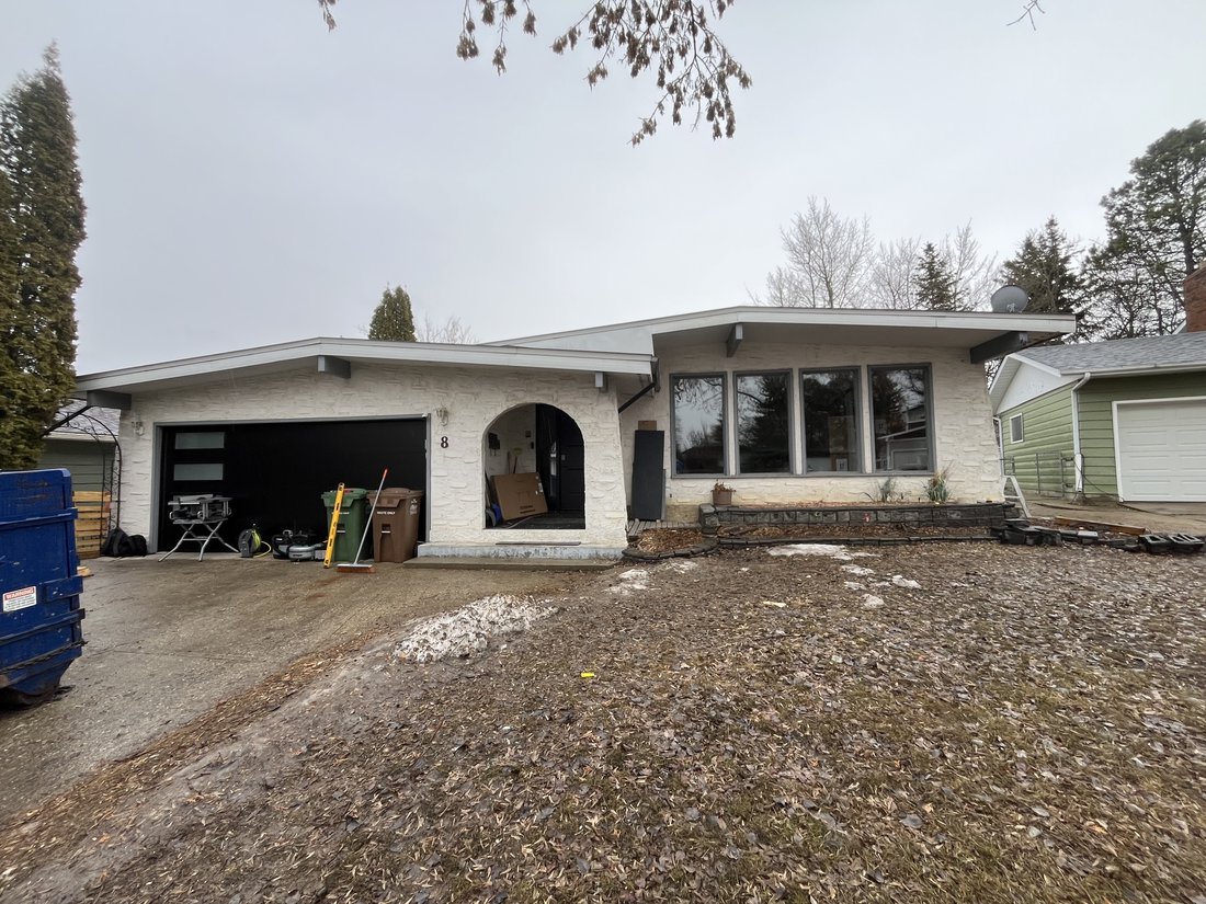 Same bungalow before renovation with white stone-textured stucco